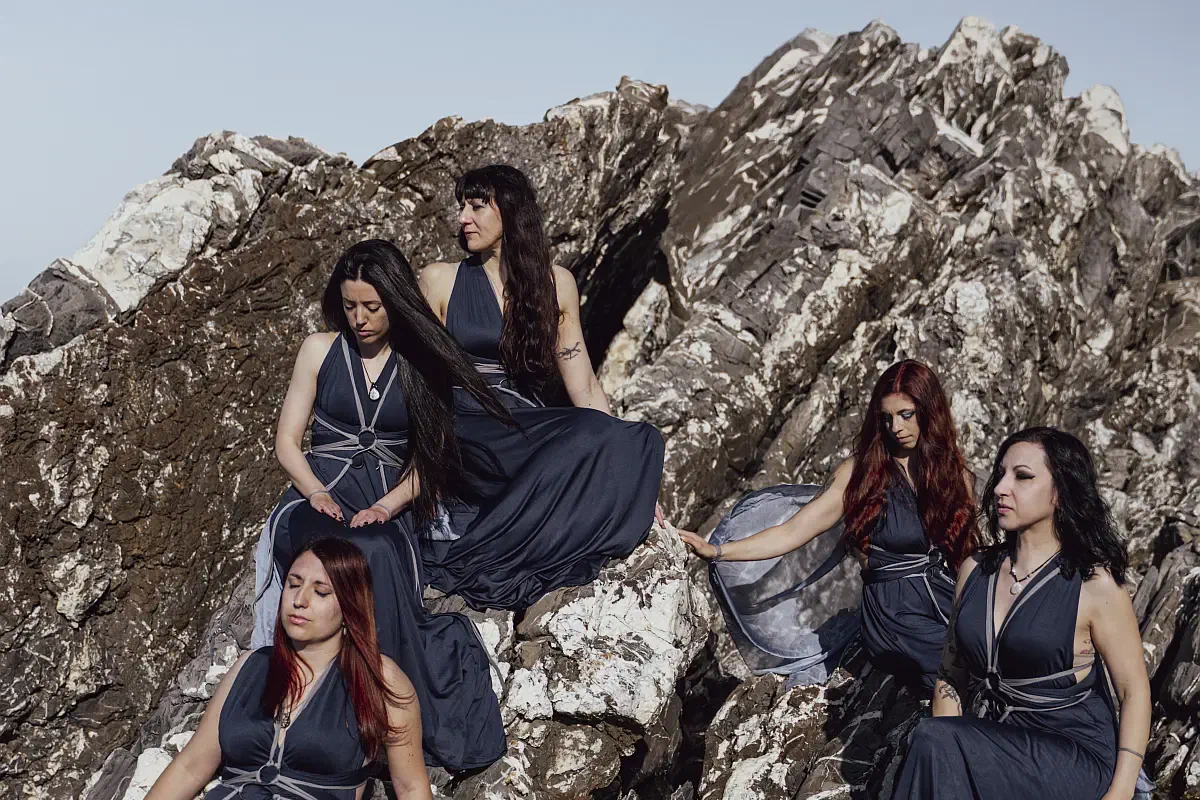 Gruppo Fairy Circle posato su una formazione rocciosa, cinque insegnanti di danza in abiti blu scuro con dettagli argento, ritratte in atmosfera naturale e armoniosa